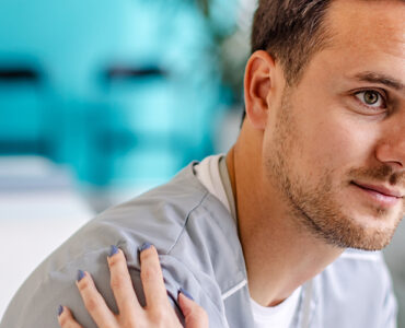 A young man sitting in a doctor's office, being consoled by the nurse.