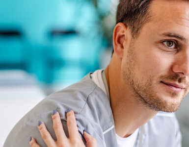 A young man sitting in a doctor's office, being consoled by the nurse.
