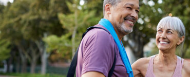 A middle-aged man and woman standing together outdoors after a workout.