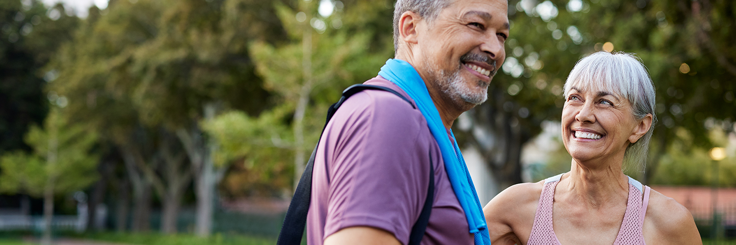 A middle-aged man and woman standing together outdoors after a workout.