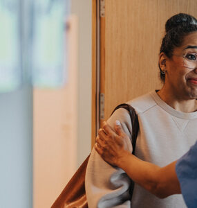 A black woman talking to a surgeon in a clinical setting.