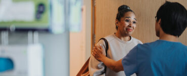 A black woman talking to a surgeon in a clinical setting.