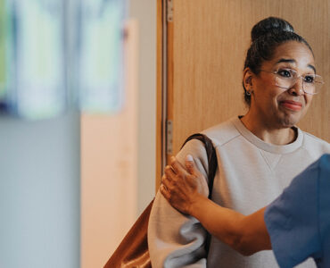 A black woman talking to a surgeon in a clinical setting.