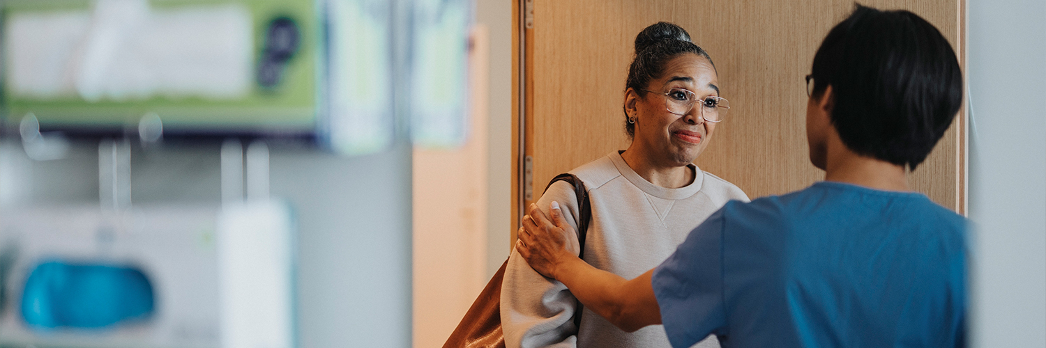 A black woman talking to a surgeon in a clinical setting.