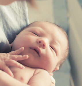 Mother holding newborn baby in hospital.