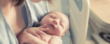 Mother holding newborn baby in hospital.