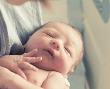 Mother holding newborn baby in hospital.