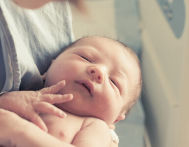 Mother holding newborn baby in hospital.