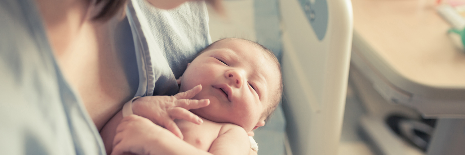 Mother holding newborn baby in hospital.