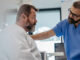 A middle-aged man awaiting surgery in the hospital, with his doctor's hand on his shoulder.