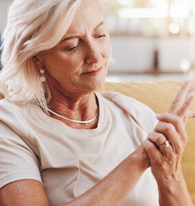 Elderly woman with hand pain sitting on couch