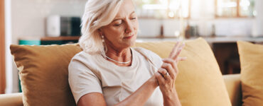 Elderly woman with hand pain sitting on couch
