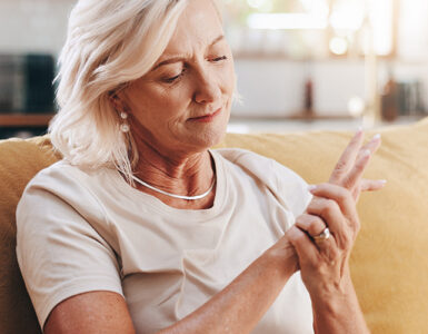Elderly woman with hand pain sitting on couch