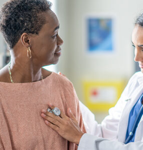 An older black woman being examined by a female doctor in a medical office.