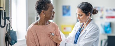 An older black woman being examined by a female doctor in a medical office.