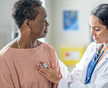 An older black woman being examined by a female doctor in a medical office.