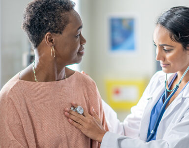 An older black woman being examined by a female doctor in a medical office.