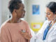 An older black woman being examined by a female doctor in a medical office.