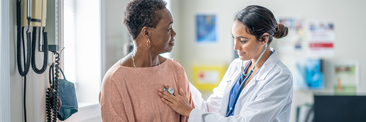 An older black woman being examined by a female doctor in a medical office.