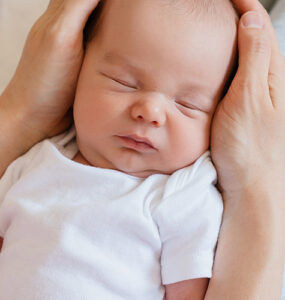 A newborn baby sleeping in his mother's arms.