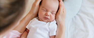 A newborn baby sleeping in his mother's arms.