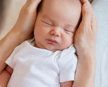 A newborn baby sleeping in his mother's arms.