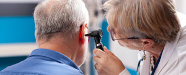 A doctor checking older man's hearing