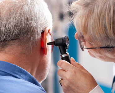 A doctor checking older man's hearing