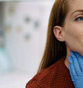 A female patient in her 40s having her neck and thyroid gland examined by a female doctor.