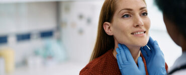 A female patient in her 40s having her neck and thyroid gland examined by a female doctor.