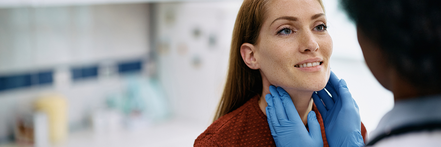 A female patient in her 40s having her neck and thyroid gland examined by a female doctor.