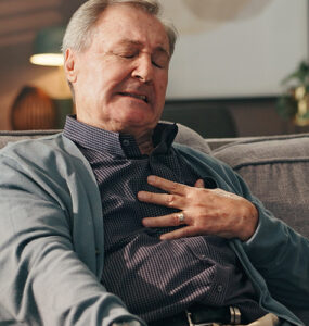 Man sitting on couch experiencing chest ache