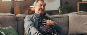 Man sitting on couch experiencing chest ache