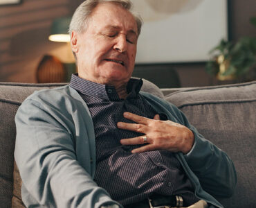 Man sitting on couch experiencing chest ache