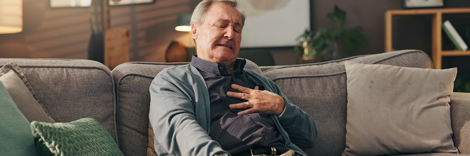 Man sitting on couch experiencing chest ache