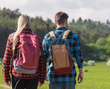 A young man and woman walking outdoors past a sign with a tick icon on it.