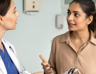 A woman in her 30s speaking to her female doctor in a medical office.