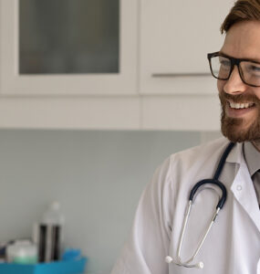 A male patient in his 40s speaking to a male doctor in his medical office, both smiling.