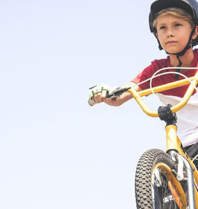 An adolescent boy riding an e-bike and wearing a helmet.