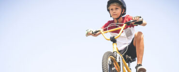 An adolescent boy riding an e-bike and wearing a helmet.