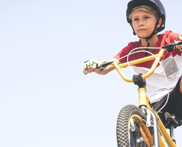 An adolescent boy riding an e-bike and wearing a helmet.