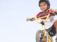 An adolescent boy riding an e-bike and wearing a helmet.