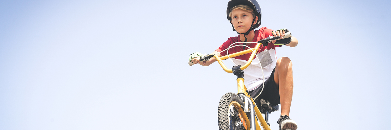 An adolescent boy riding an e-bike and wearing a helmet.