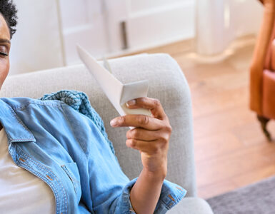 Black woman sitting on couch having a hot flash.