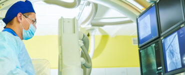 Interventional radiologist looking at computer with imaging scans