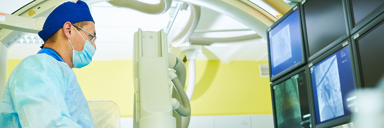 Interventional radiologist looking at computer with imaging scans