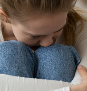 Teenage girl sitting on couch having panic attack