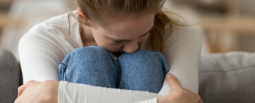 Teenage girl sitting on couch having panic attack