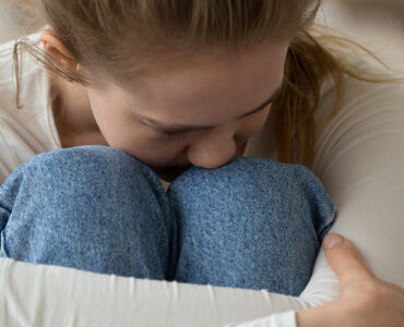Teenage girl sitting on couch having panic attack