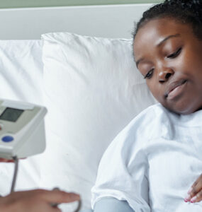 Black pregnant woman in hospital bed being checked by doctor